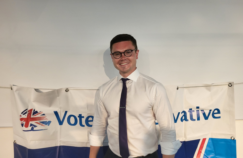 Freddie Downing standing in front of a banner that says "Vote Conservative"